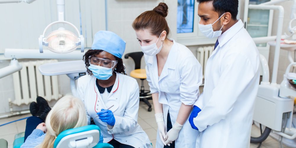 Health and healthcare. A multinational group of dentists examines x-rays in the presence of a patient. Practice at a medical university.